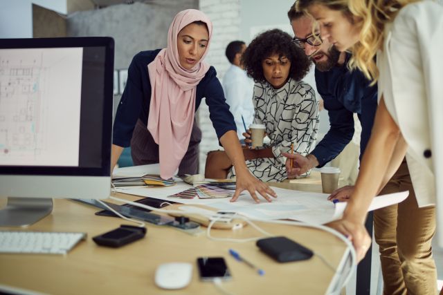 People working in an office around a desk