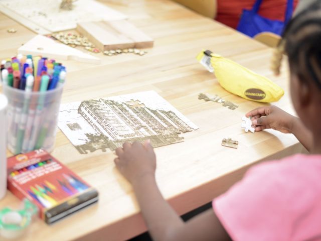 Girl making a puzzle of her apartment building